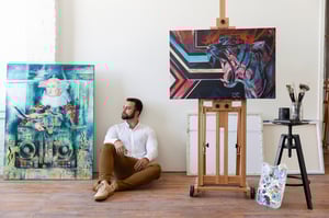 man sitting in room with art on canvas