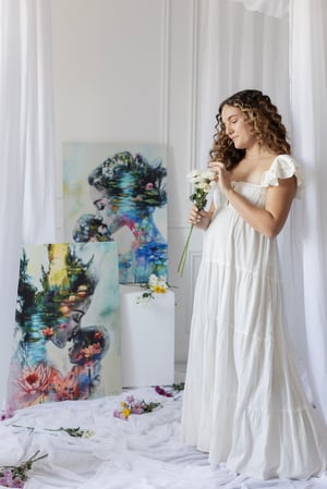 Woman in whaite dress standing in front of paintings