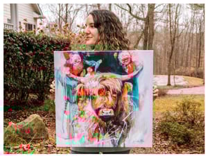 girl holding painitng of cow with flowers teal pink and tan