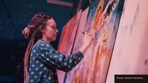 Woman in blue painting on a pink canvas