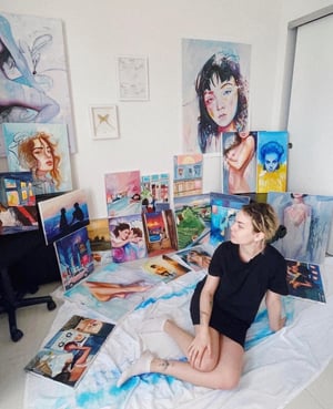 Girl sitting in art studio among colorful paintings
