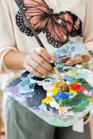 Hand in front of colorful paint pallet 
