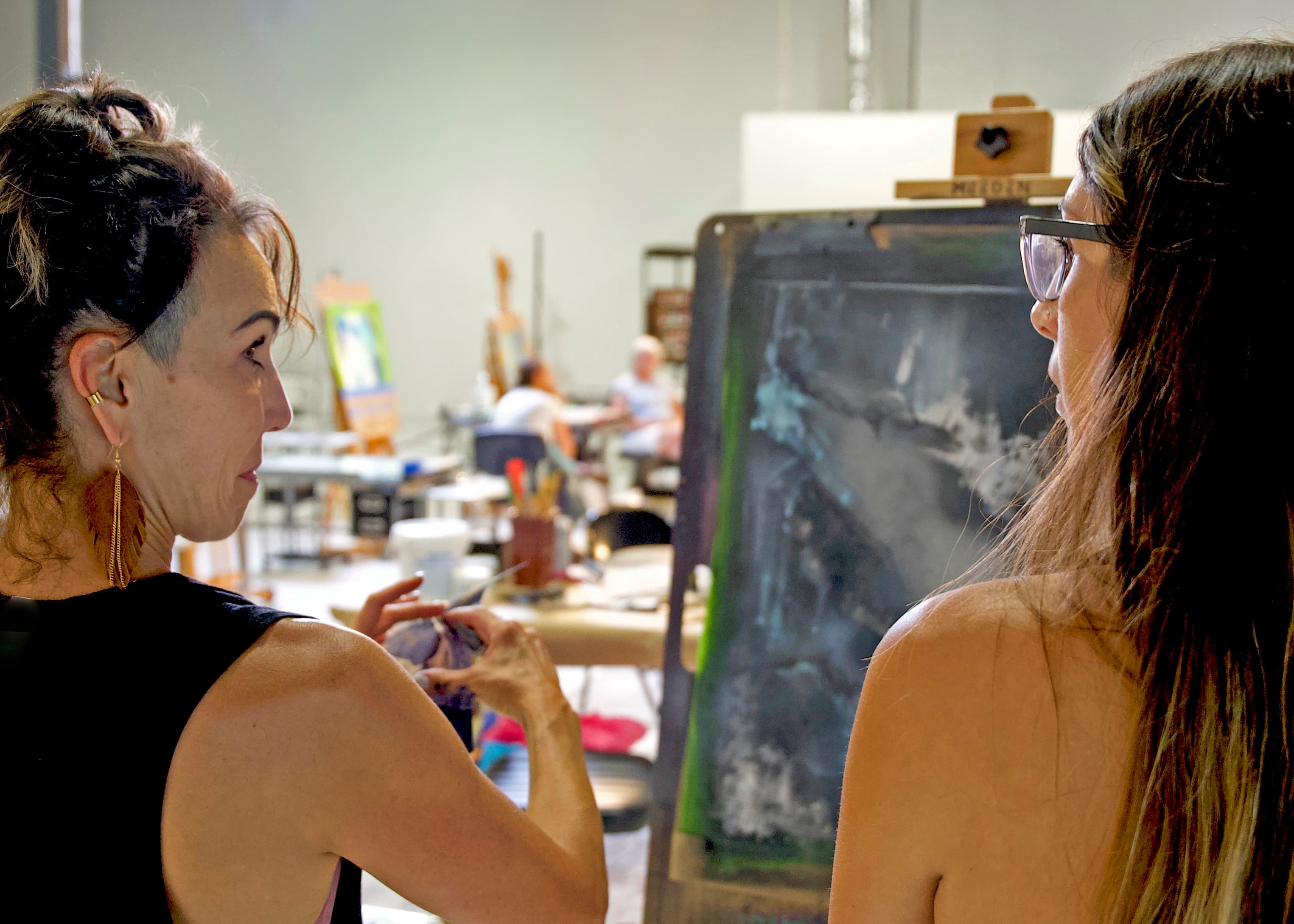 An instructor giving feedback to a student at the easel