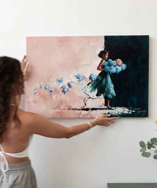 Artist hanging a finished painting of a girl in a blue dress holding flowers
