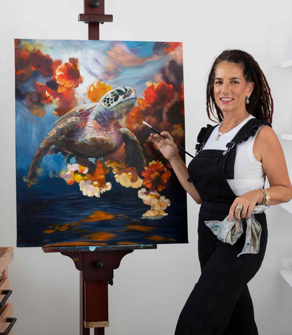 Elli Milan in her studio beside a colorful turtle painting