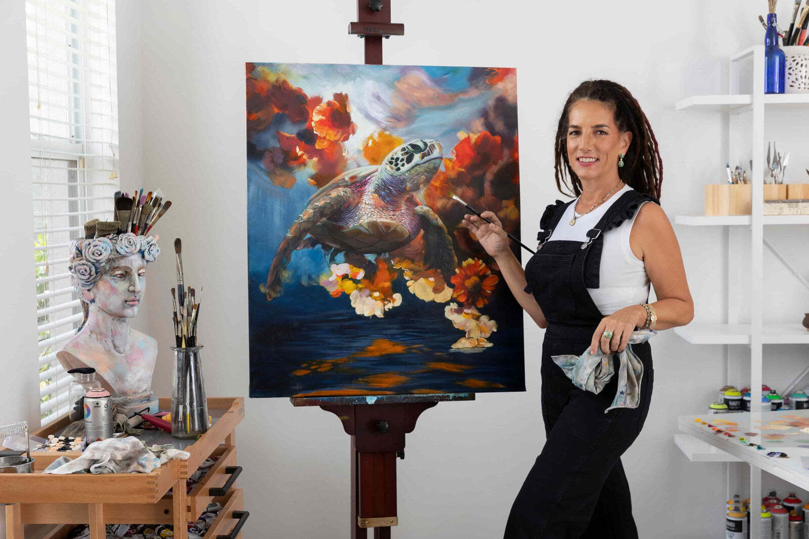 Elli Milan standing beside a finished turtle painting in her studio